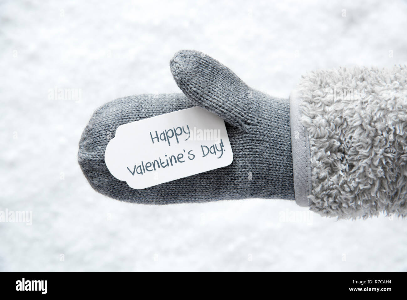 Guante de lana con etiqueta con texto en inglés Feliz Día de San Valentín.  Fondo blanco de nieve Fotografía de stock - Alamy