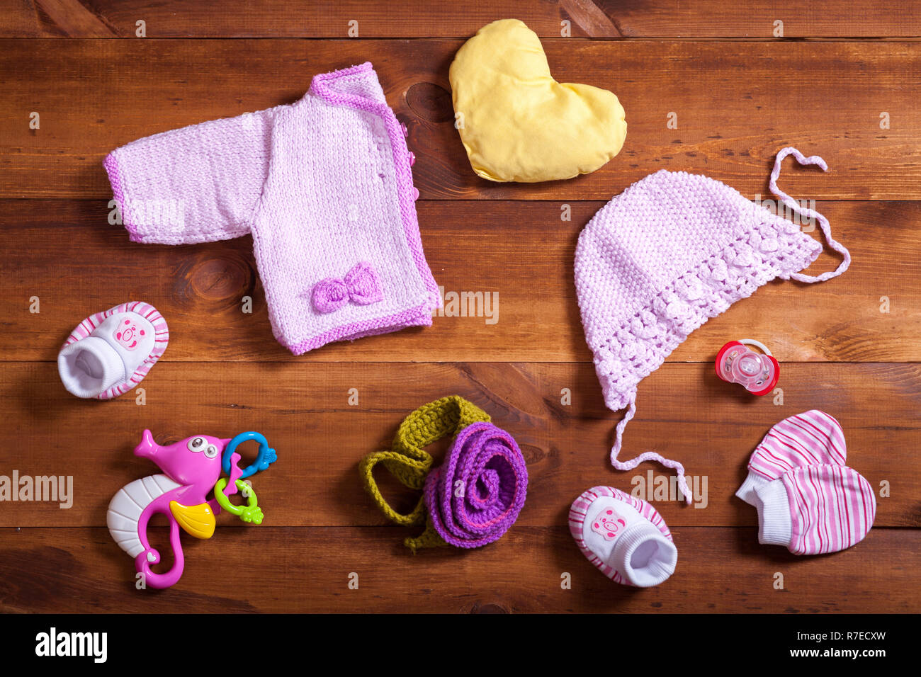 Concepto de conjunto de ropa de bebé, Rosa ropa tejida, juguetes y accesorios de madera color marrón de fondo, niño recién nacido paño para joven, moderno baby sh Fotografía de stock -