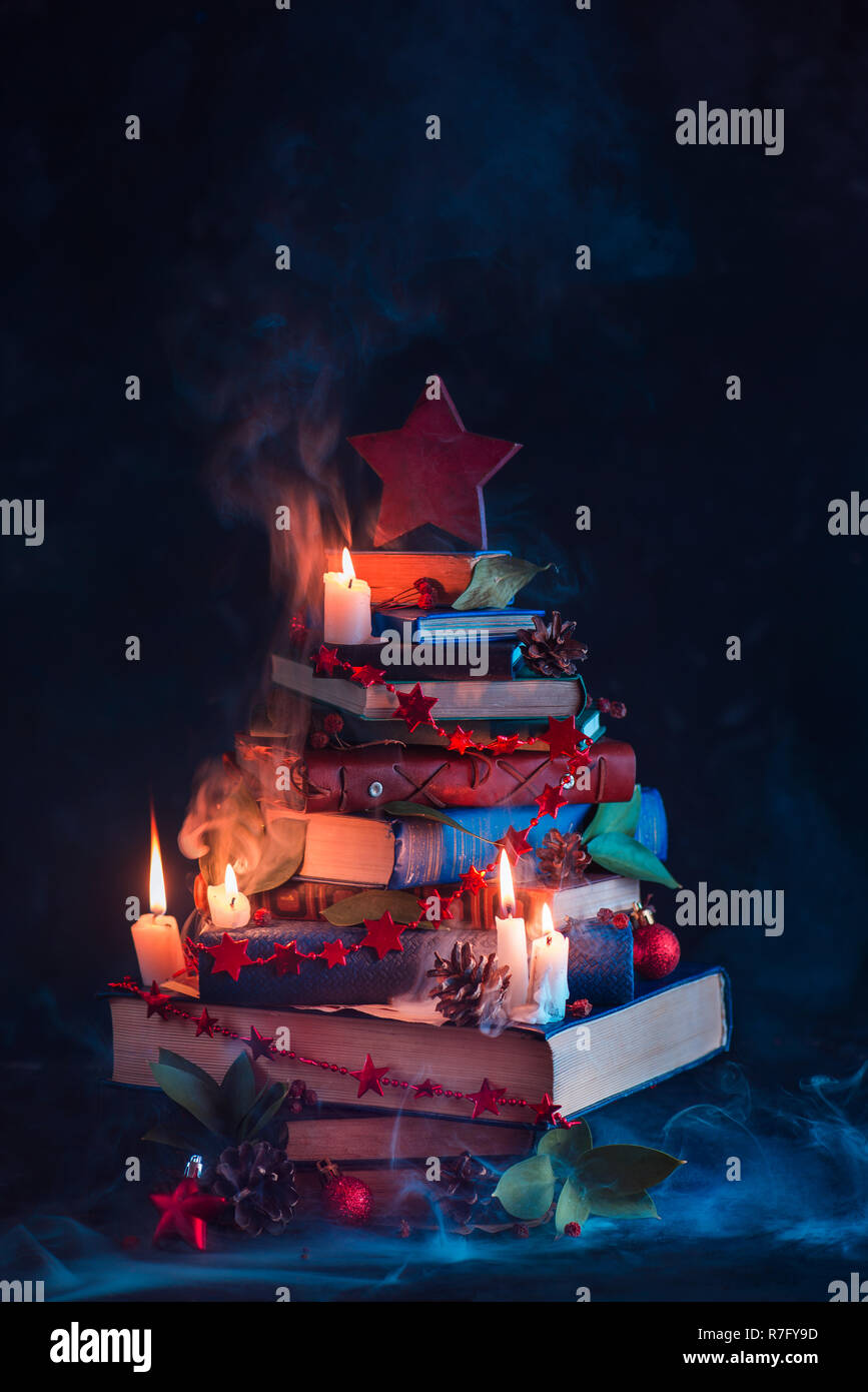 Árbol de Navidad hecho de libros con velas y misterioso humo. Decoraciones de invierno para los lectores y nerds concepto Foto de stock