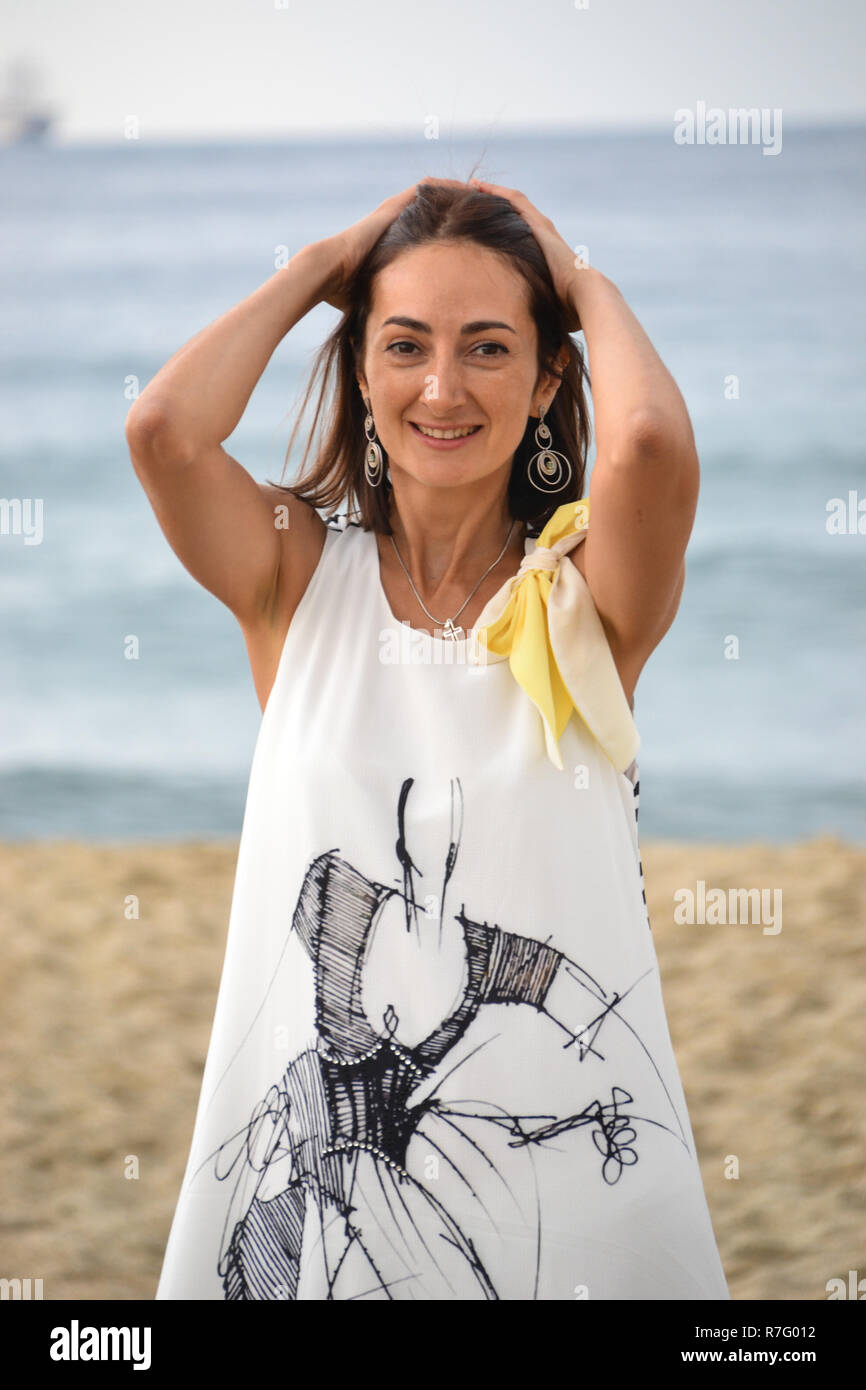 Hermosa mujer morena rusa se encuentra en la playa de blanco vestidos  sueltos, el mar de fondo Fotografía de stock - Alamy