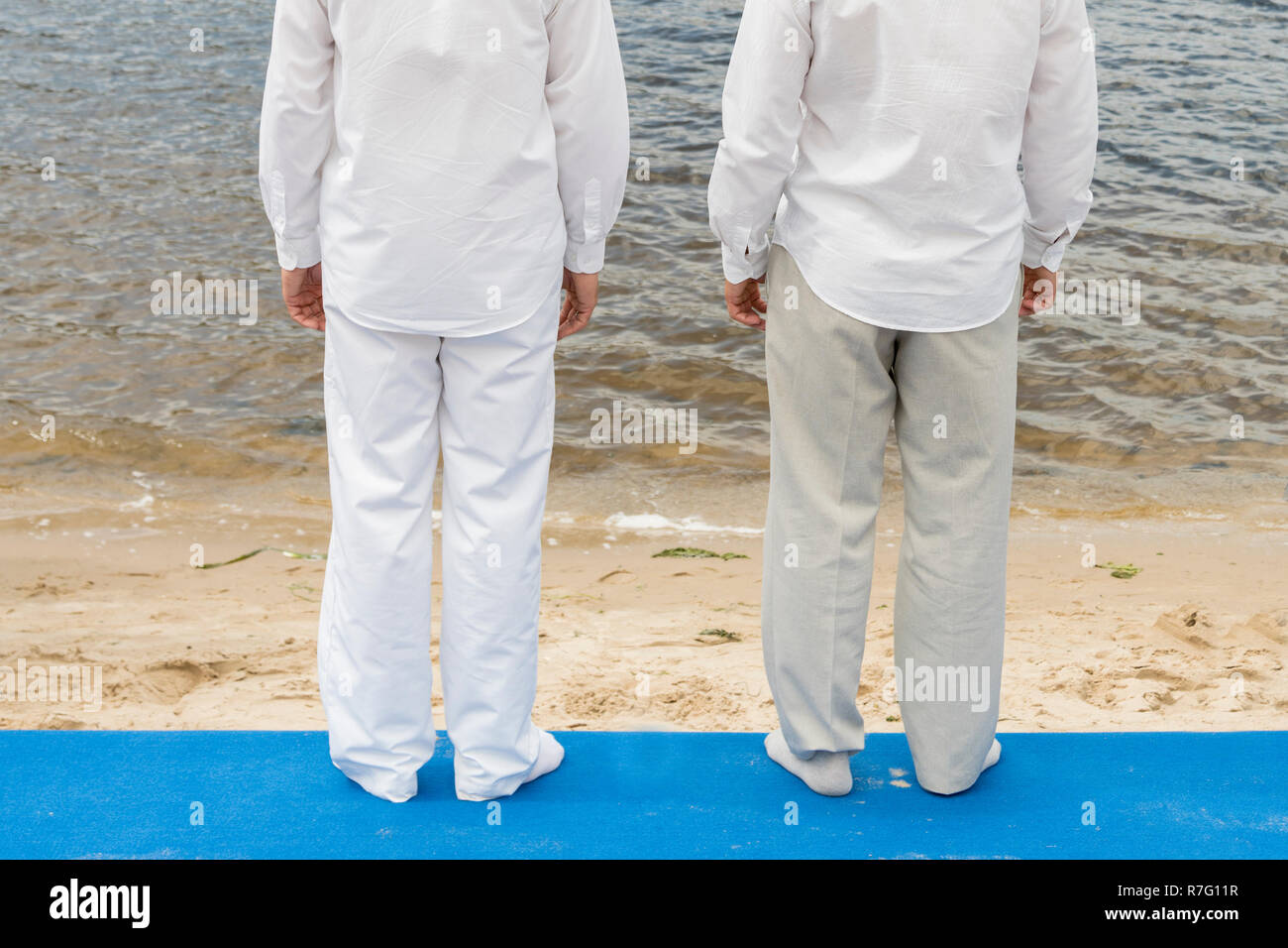 Dos hombres están el bautismo en agua. Dos hombres en ropa blanca frente de un río de stock -