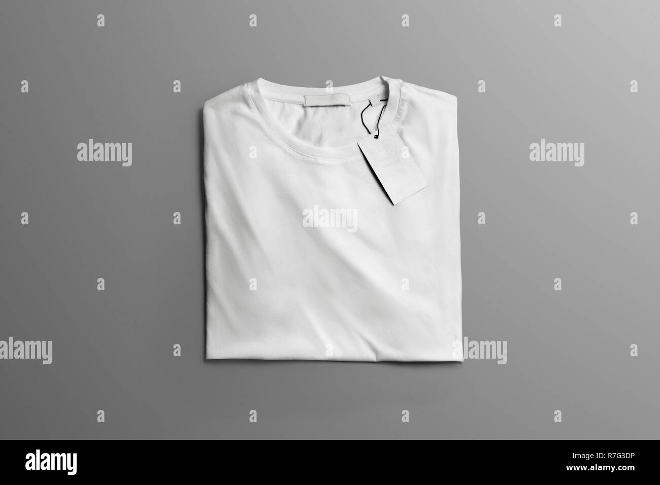 Maqueta de estudio de ropa. Doblado en blanco T-shirt yace en el fondo gris con sombras. Puede utilizar la plantilla para usted Showcase. Foto de stock