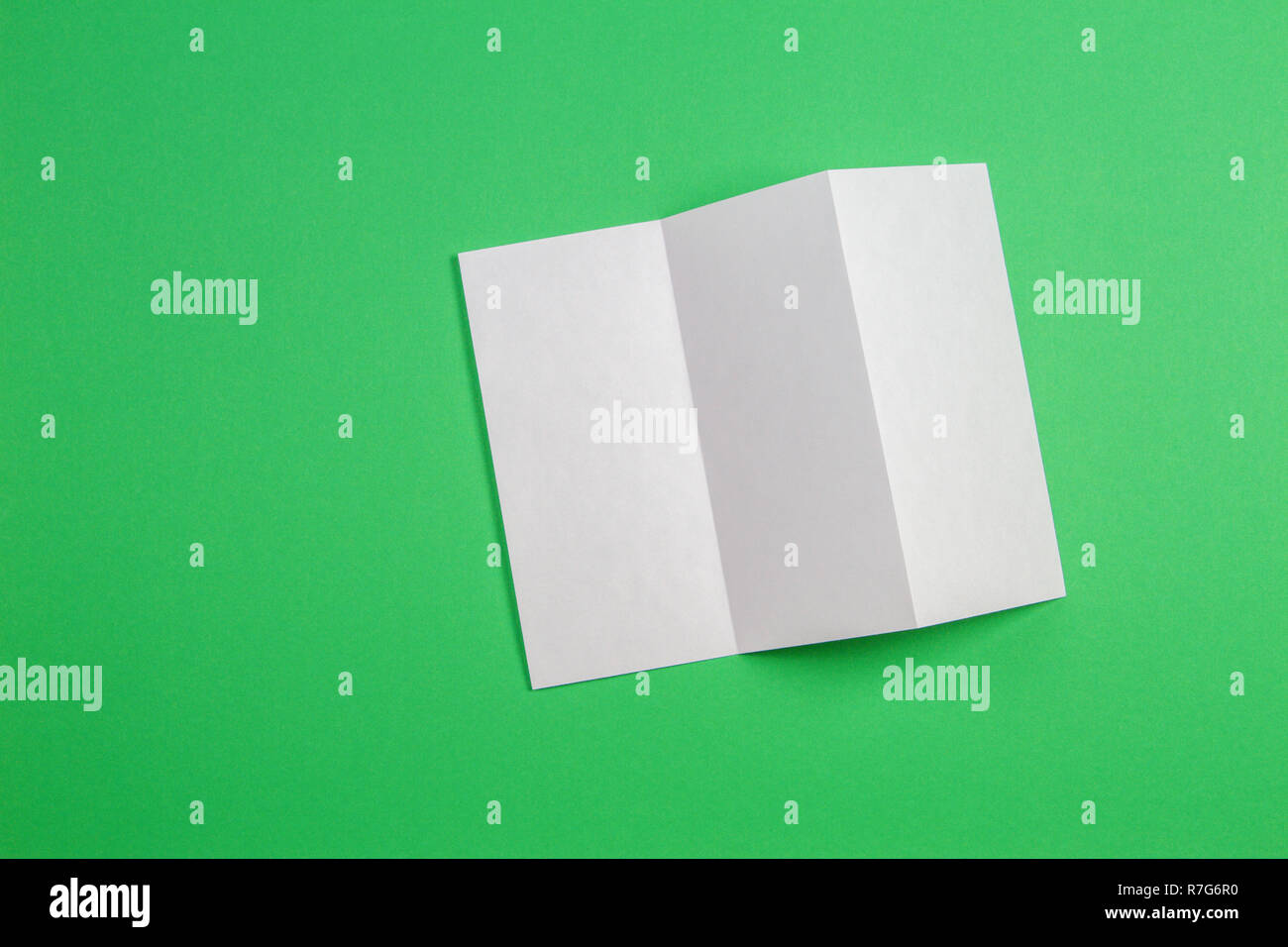 Boceto del folleto plegado triple blanco folleto sobre fondo verde. Foto de stock