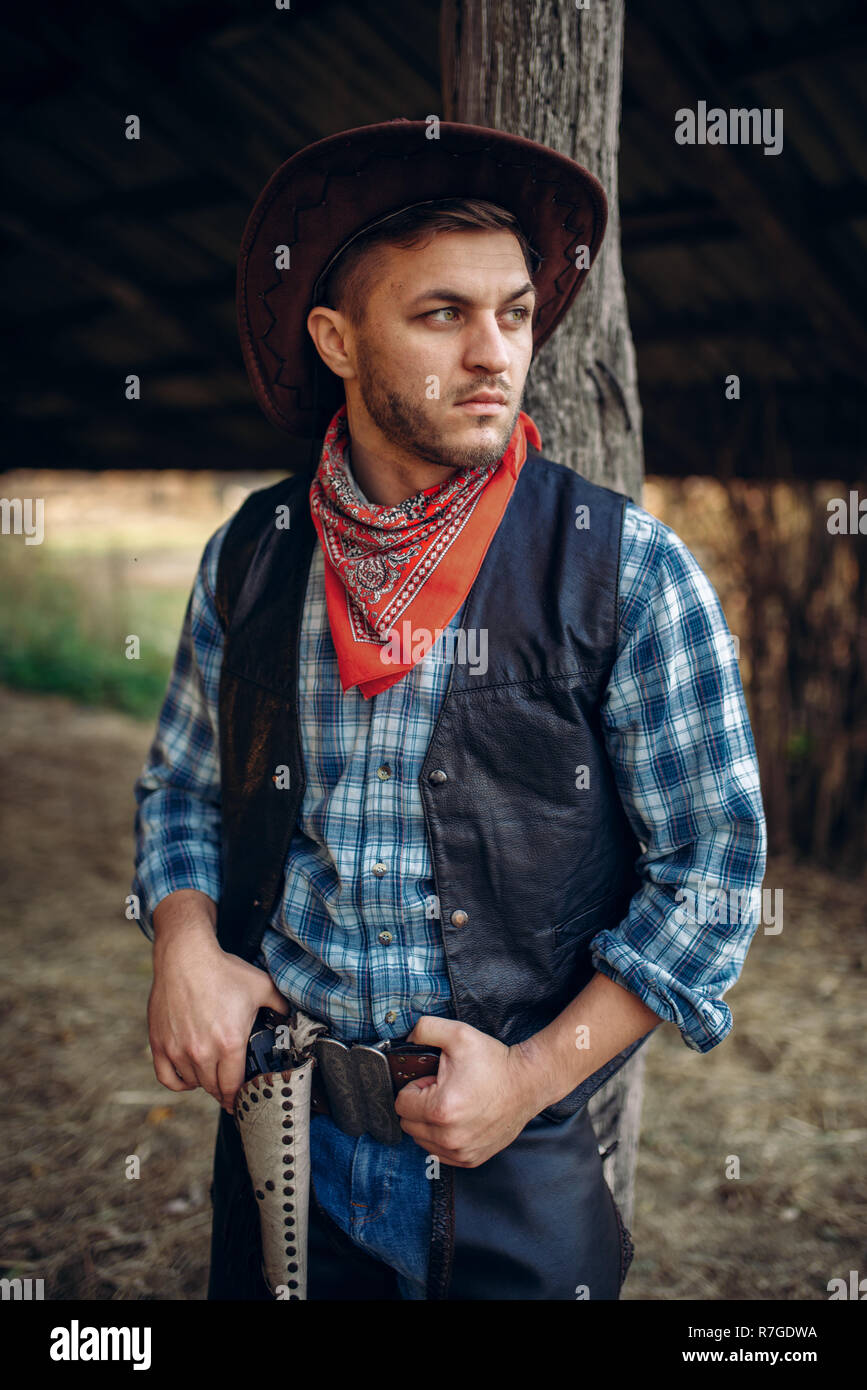 Cowboy brutal en jeans y chaqueta de cuero, rancho de Texas sobre  antecedentes, occidental. Vintage persona de sexo masculino con el  revólver, wild west lifestyle Fotografía de stock - Alamy