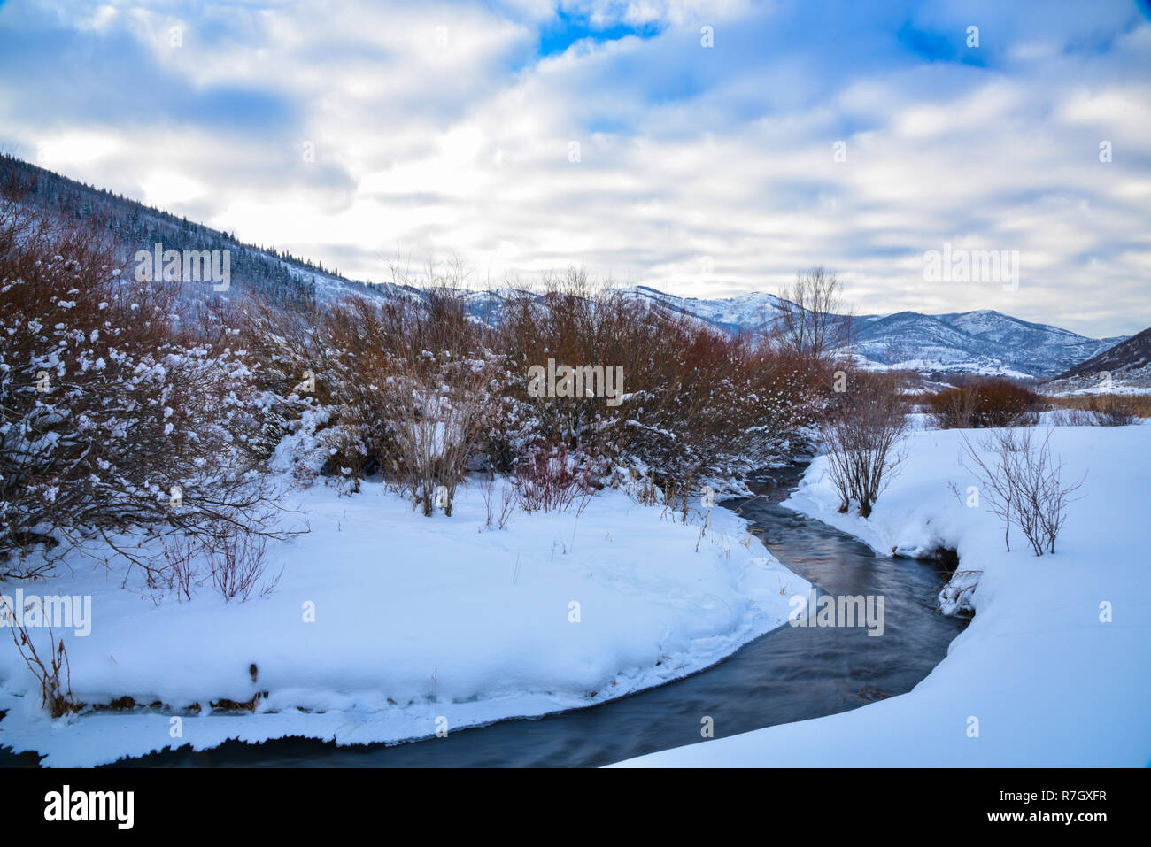 Un pequeño arroyo fluye a través de una pradera con nieve cerca de Park City, Utah. Foto de stock
