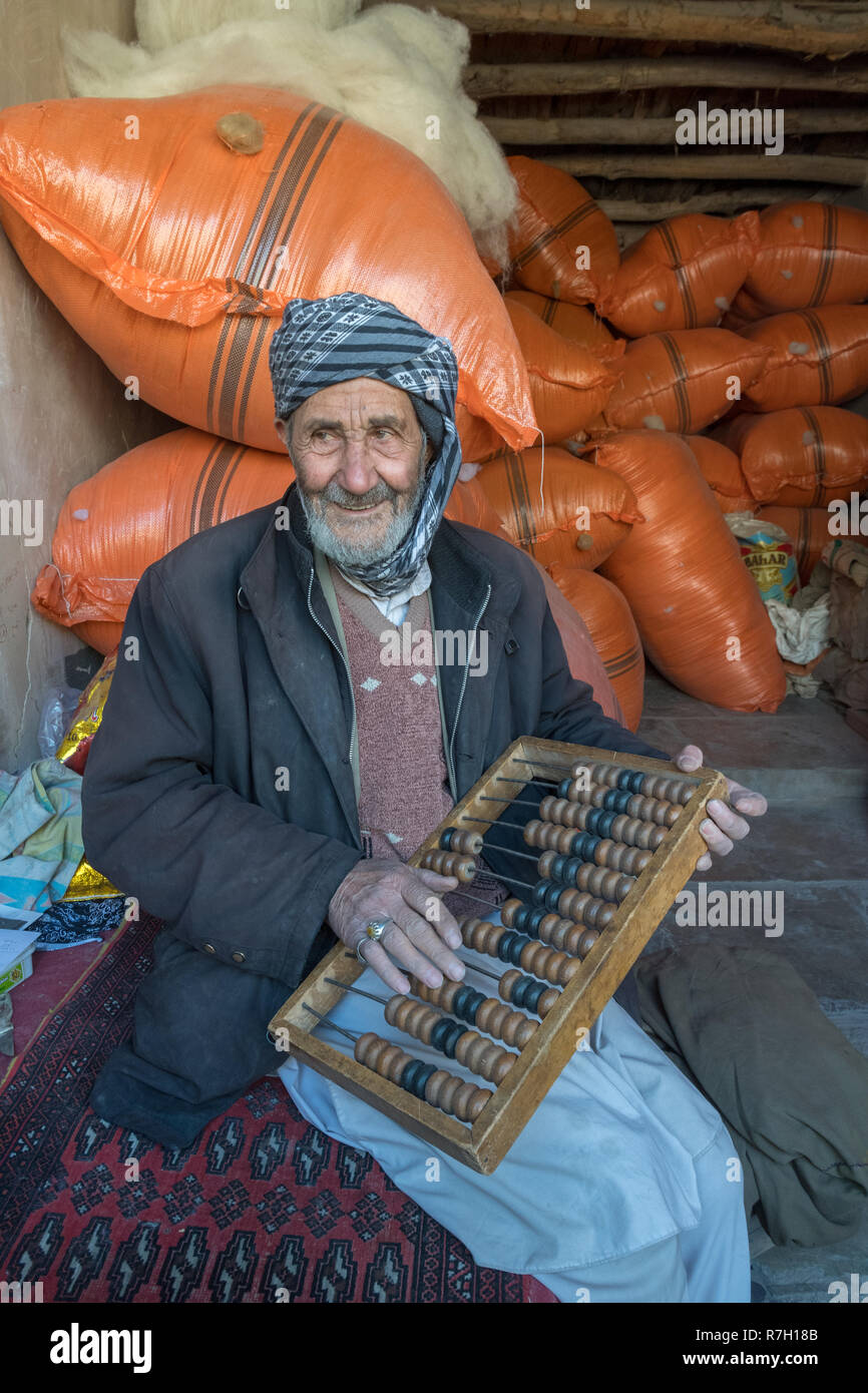 Ancianos Bazar Tendero con Abacus y bolsas de cereales en el fondo, Herat, la provincia de Herat, Afganistán Foto de stock