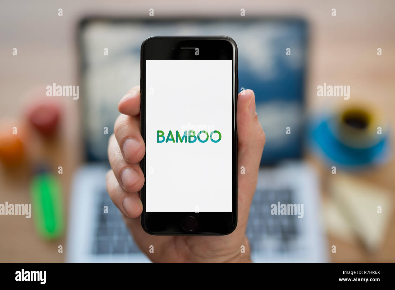 Un hombre mira el iPhone que muestra el logotipo de bambú (uso Editorial solamente). Foto de stock