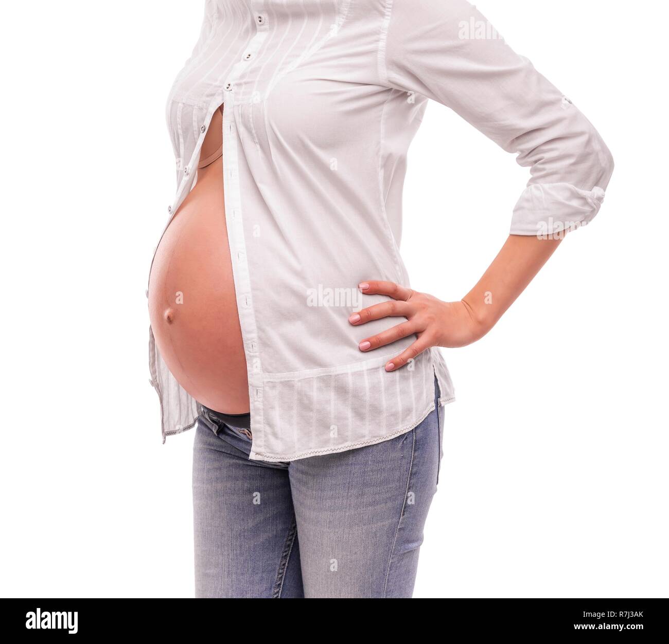 La mujer embarazada en una camisa blanca y jeans sobre un fondo blanco  Fotografía de stock - Alamy
