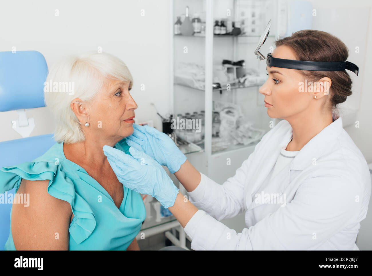 Otorrinolaringólogo examina la garganta de la mujer de más edad en la clínica Foto de stock