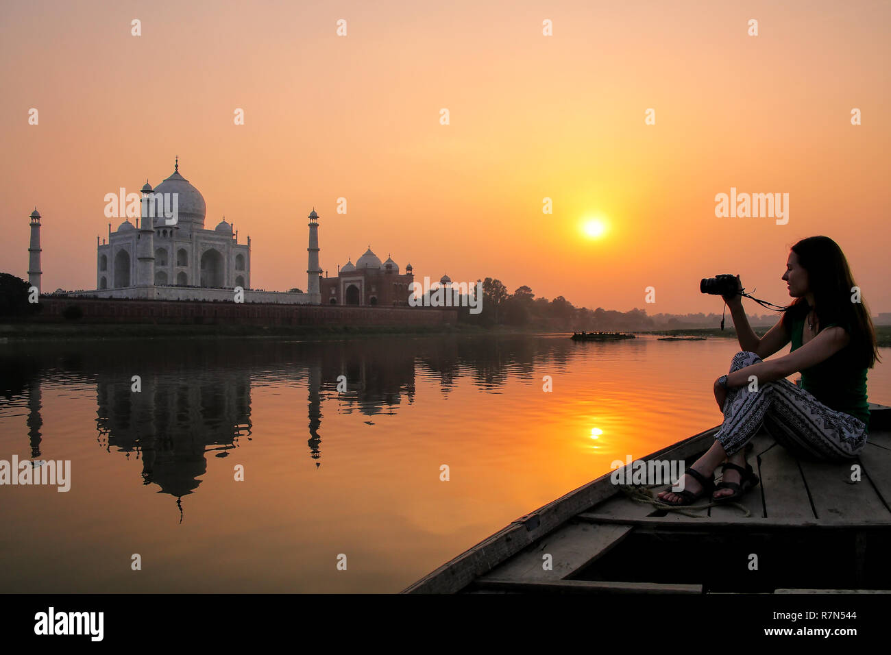 Mujer viendo la puesta de sol sobre el Taj Mahal desde un barco, Agra, India. Fue construido en 1632 por el emperador Shah Jahan como un memorial de su segunda esposa Mumtaz Mah Foto de stock