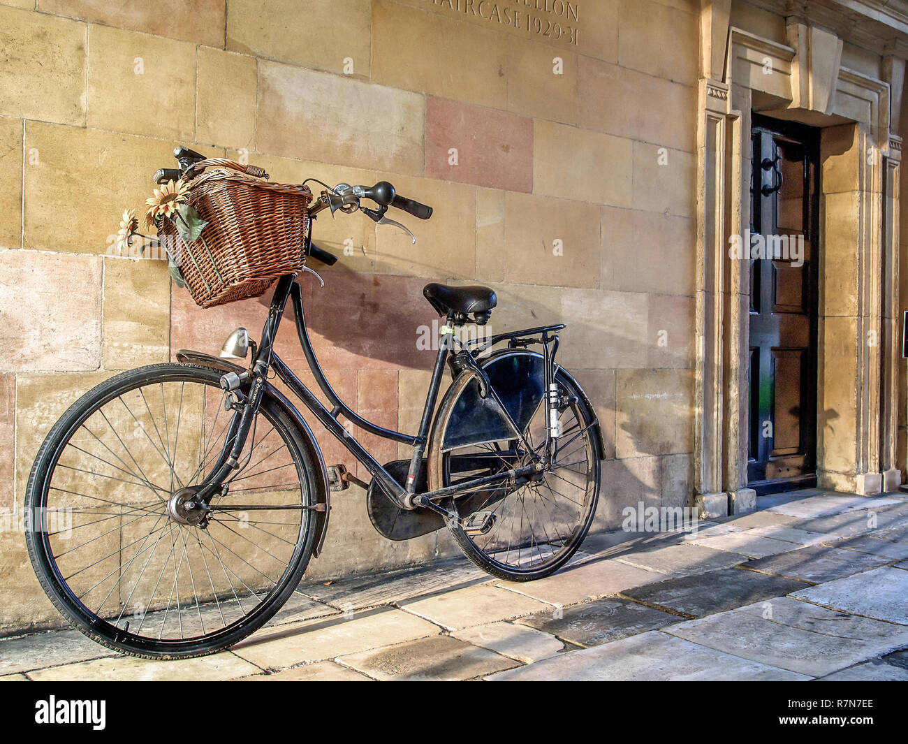 Bicicleta con cesta de compras aparcada en el recinto de la Universidad en Cambridge, Reino Unido Foto de stock