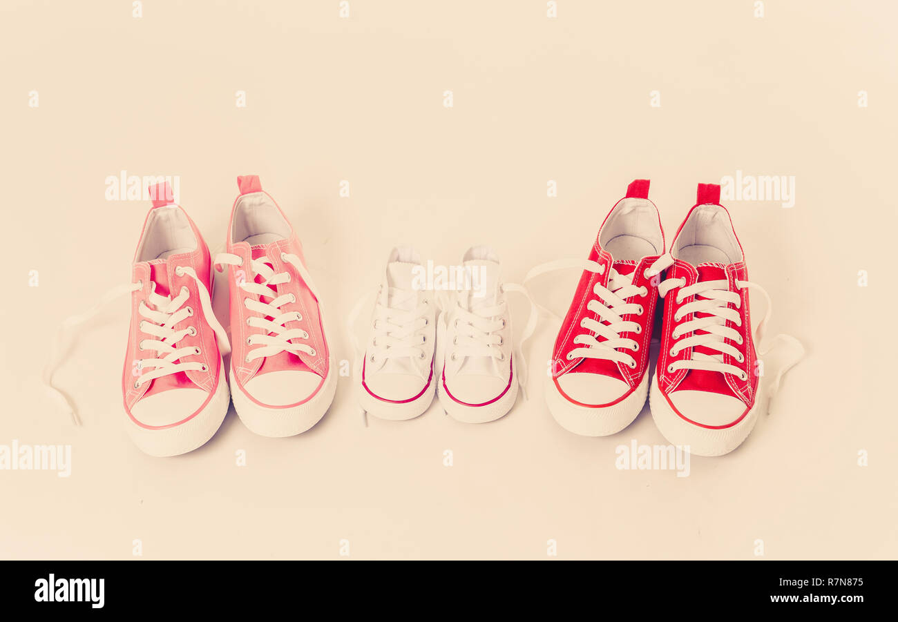 Imagen conceptual de gumshoes sneakers de dos madres e hijo hija aislado sobre fondo blanco copia espacio en la moderna solidaridad familiar Crianza Foto de stock