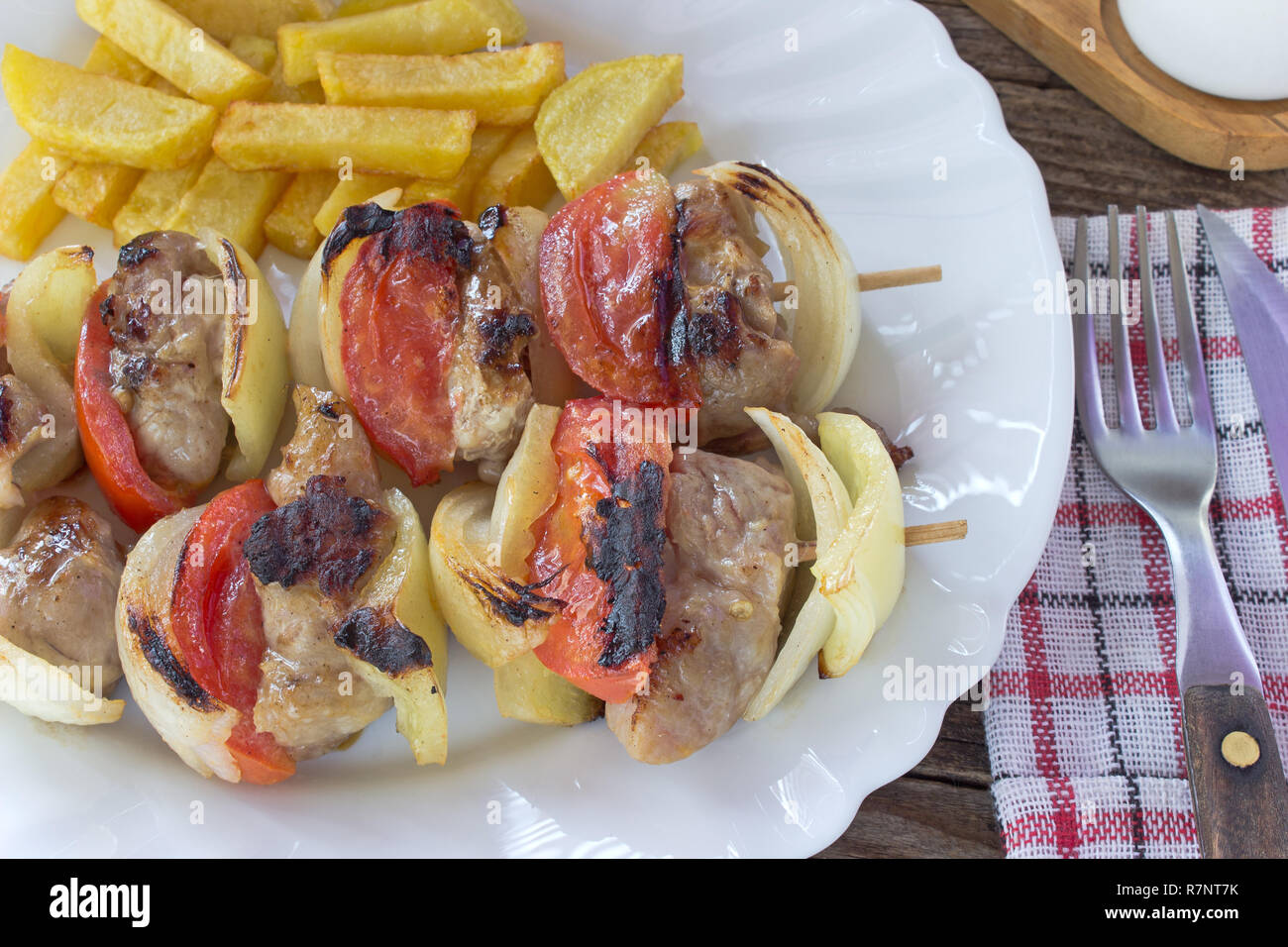 Carne asada con vegetales sobre palos en la placa en la tabla Foto de stock