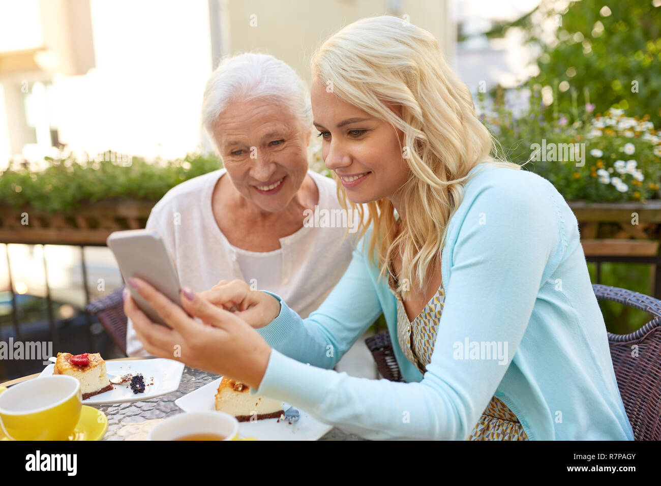 Hija y madre senior con el smartphone en el cafe Foto de stock