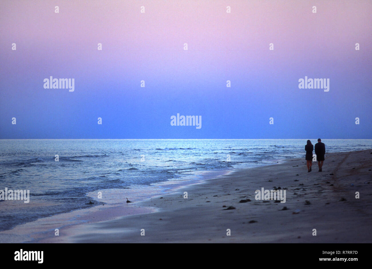 Una pareja caminando en la playa después del atardecer en Djerba, Túnez Foto de stock