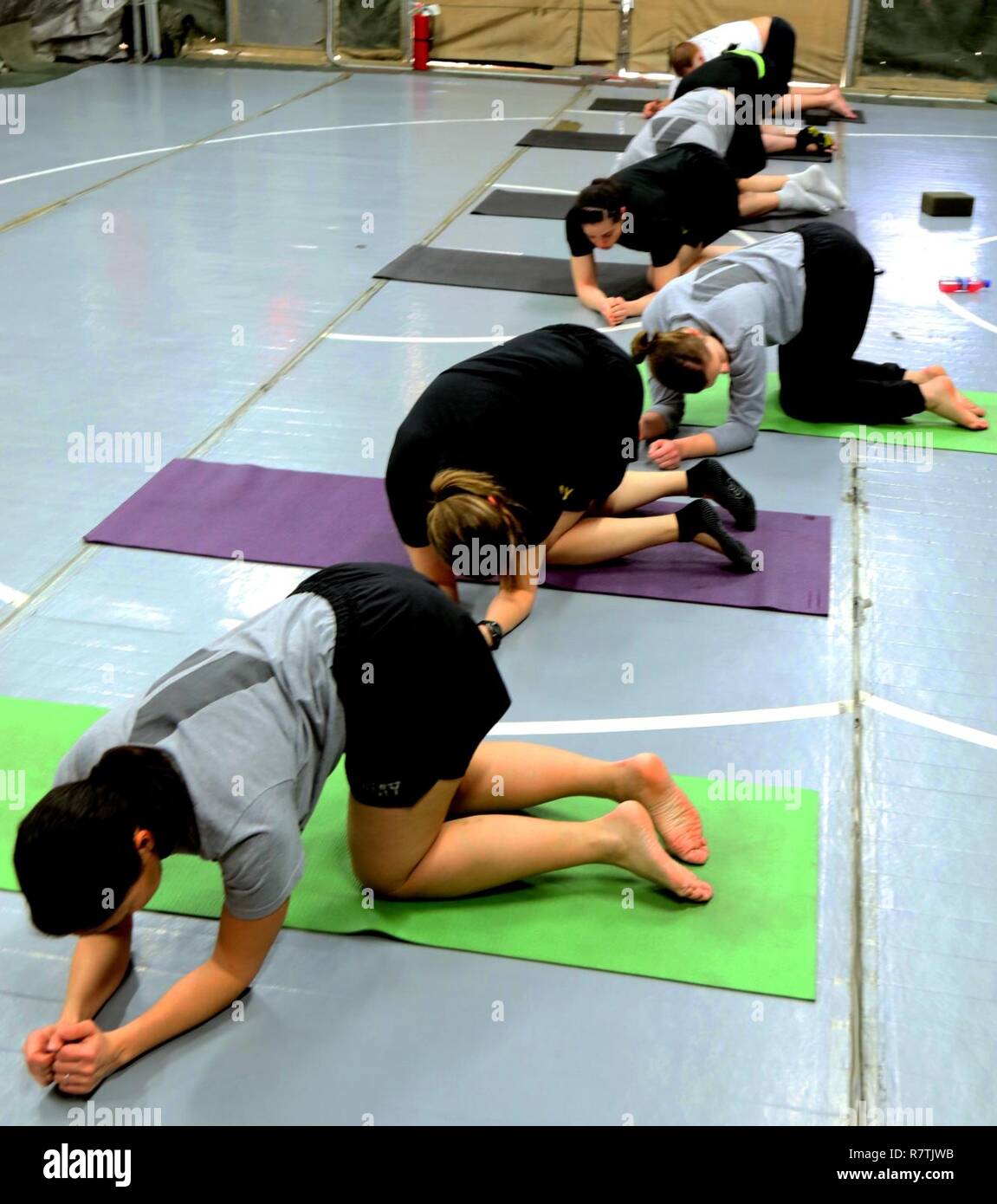 Los soldados participar en una clase de yoga para su sesión de entrenamiento físico por la mañana, mientras que el despliegue al aeródromo de Bagram, Afganistán. Algunos soldados han encontrado el yoga para ser una forma eficaz de alivio de tensión en un entorno implementado mientras que todavía siendo un arduo entrenamiento. Foto de stock