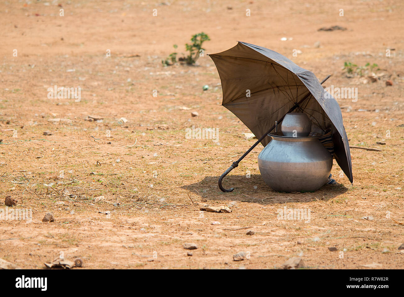 Un paraguas matices de una pila de almacenamiento de aluminio ollas de sus contenidos se calientan demasiado desde mediados días de sol Fotografía de stock - Alamy