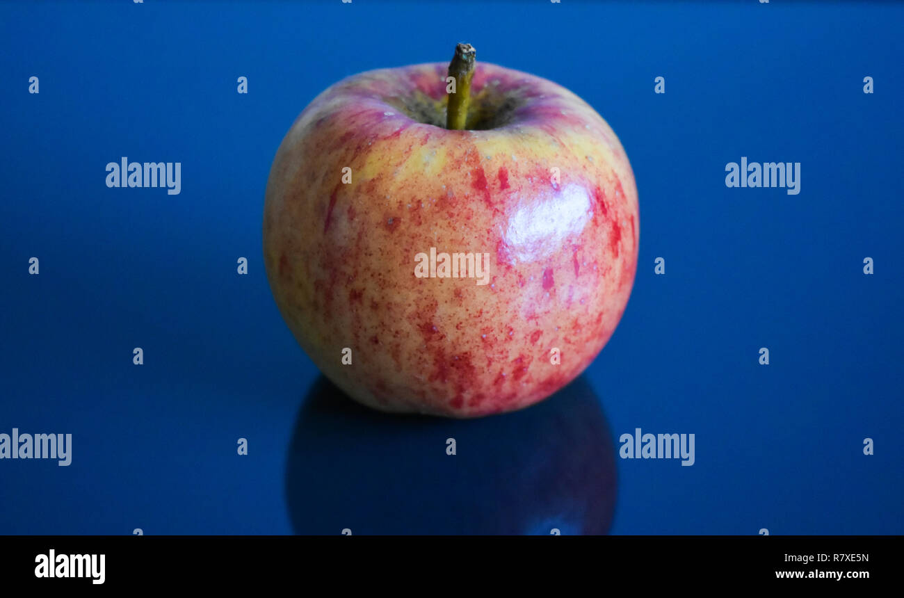 Una manzana en una superficie de espejo negro Foto de stock