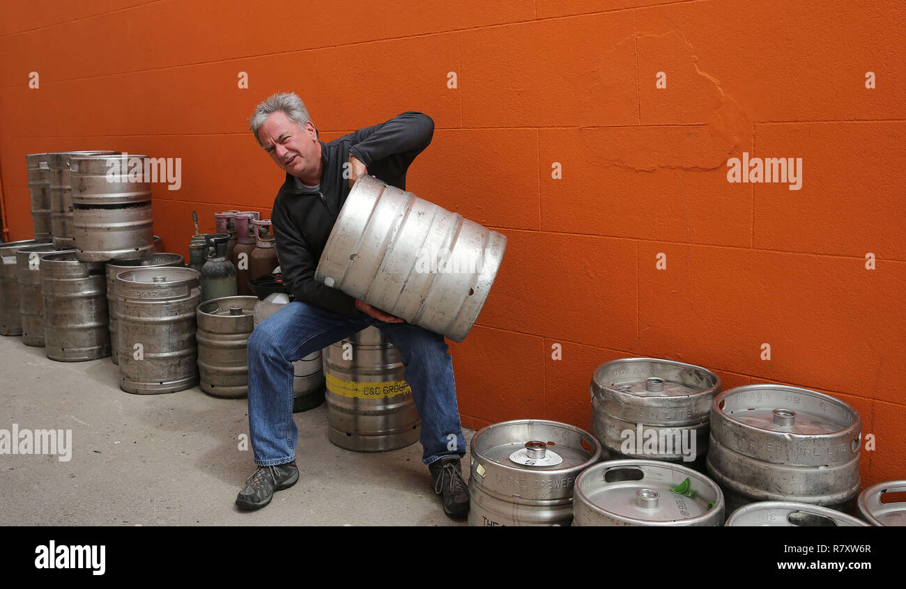 Un hombre de 60 años se lamenta de la vacuidad de los barriles de cerveza que le rodean, detrás de él en un pub en Irlanda. Foto de stock