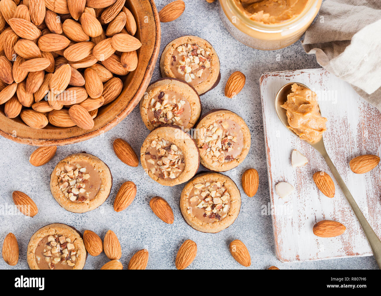 Galletas caseras galletas con almendras y nueces de mantequilla de maní en  la placa de mármol en la mesa de la cocina de fondo. Las almendras en tazón  de madera con jar