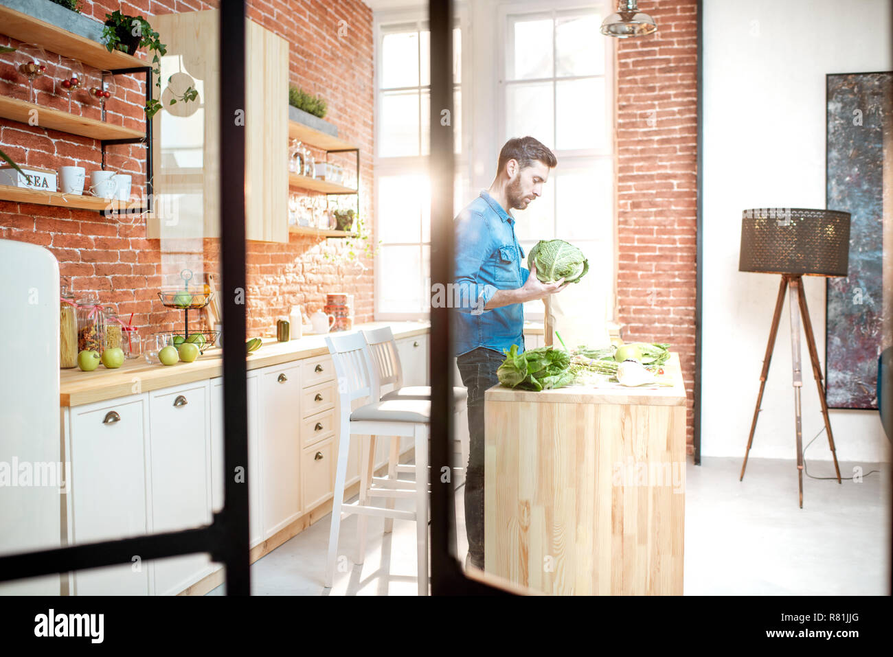 Hombre cocinar alimentos saludables, de pie en la cocina del apartamento bonito loft Foto de stock