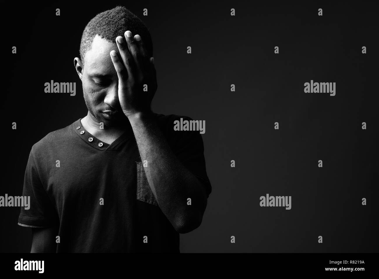 Los frustrados jóvenes hombre africano tener dolor de cabeza en blanco y negro Foto de stock