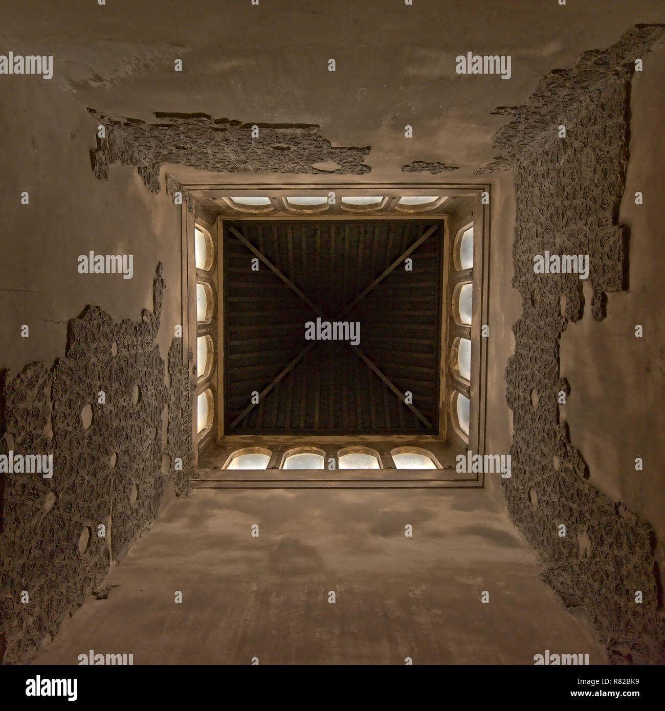 Ángulo bajo vista centrada en el interior de una torre, de palacio nazarí, con restos de tallas de piedra decorativa y ventanas de arco en la parte superior Alhamb Foto de stock