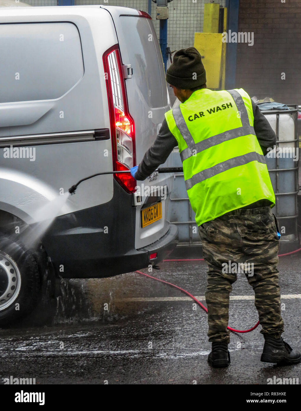 Un hombre con chorro de agua para lavar a mano un vehículo en Rotherham, South Yorkshire, Inglaterra Foto de stock