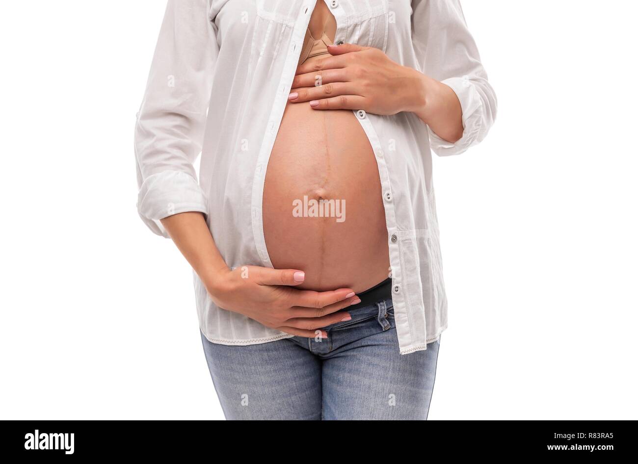 La mujer embarazada en una camisa blanca y jeans sobre un fondo blanco  Fotografía de stock - Alamy