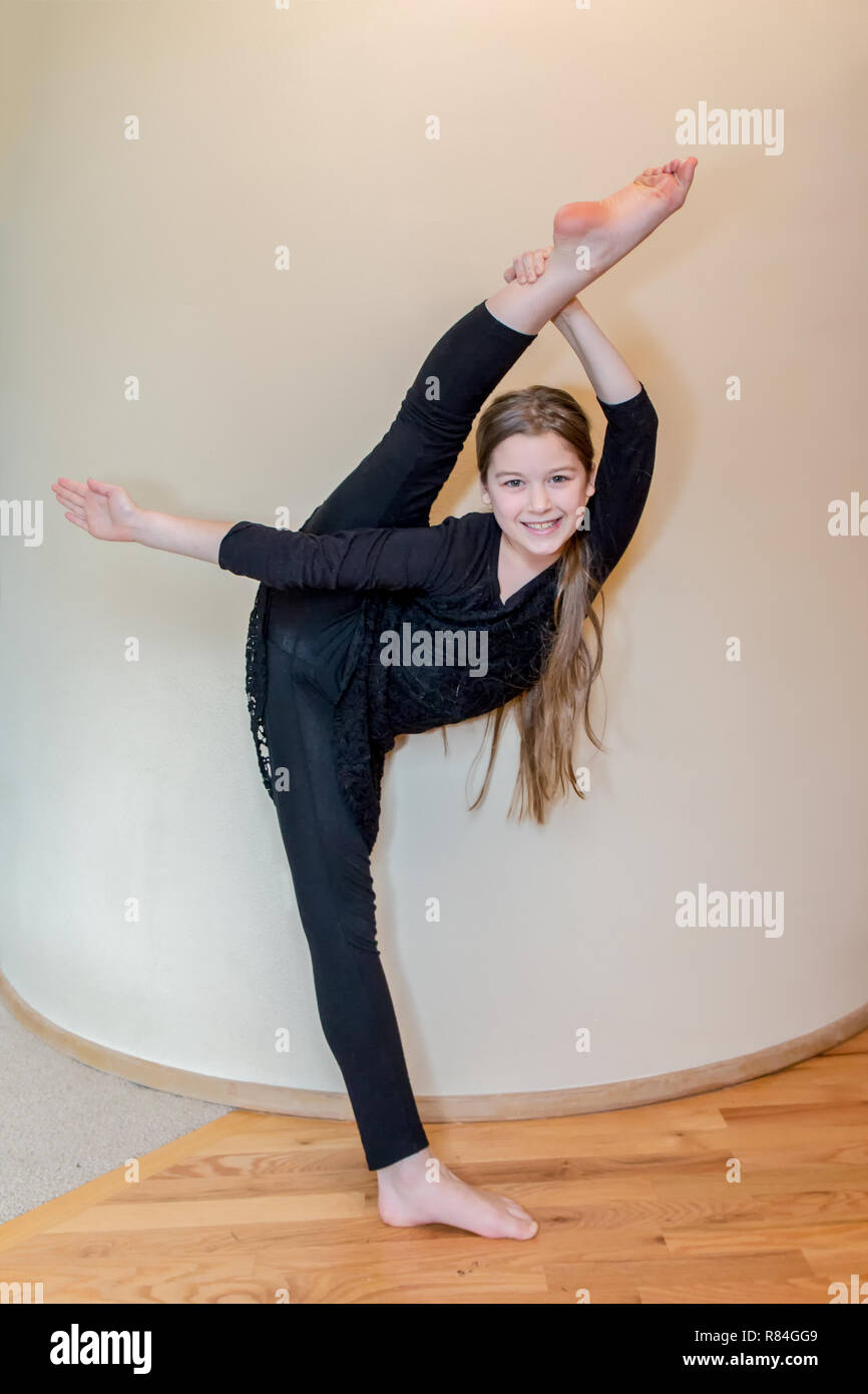 Diez años bailarina chica mostrando su flexibilidad haciendo un arco y una flecha de la pierna. (MR) Foto de stock