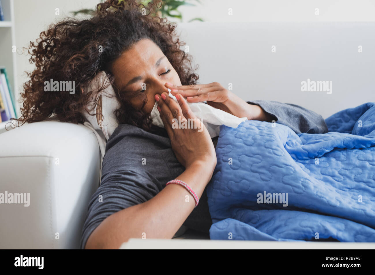 Mujer negra enfermo en casa sonarse la nariz Foto de stock