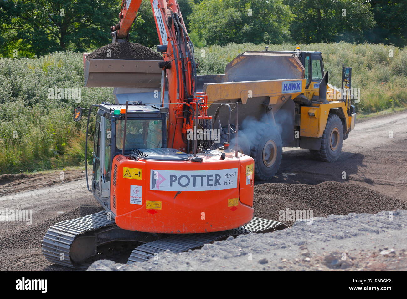 Una retroexcavadora Hitachi Komatsu HM300 de carga de un camión volquete ligero con arcilla expandida agregado que se utiliza para el rellenado en zonas sensibles. Foto de stock