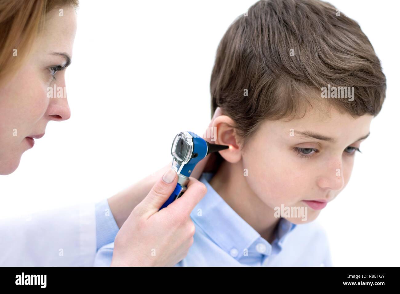 Médico examina muchacho es oído con un otoscopio. Foto de stock