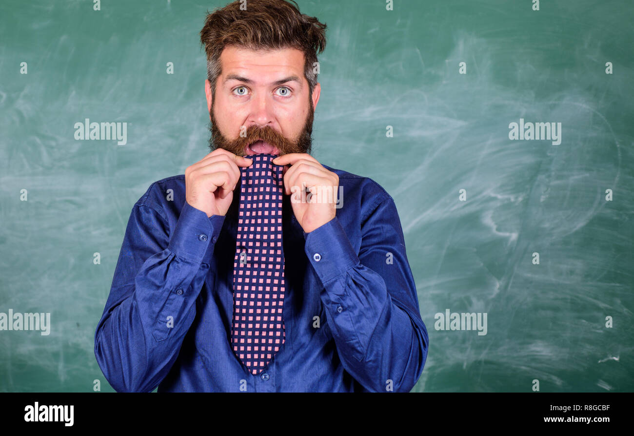 Preste atención a su comportamiento y modales. Profesor etiquette consejos profesionales de la educación moderna. Maestro se comporta unprofessionally. El hombre barbado profesor o educador come corbata de fondo de la pizarra. Foto de stock