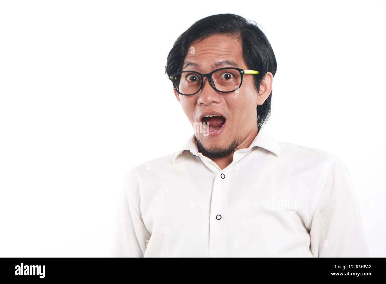 Imagen de Foto retrato de un joven gracioso empresario asiático con gafas parecía muy conmovido, cerca en vertical con gesto sorprendido, sobre blanco backgro Foto de stock