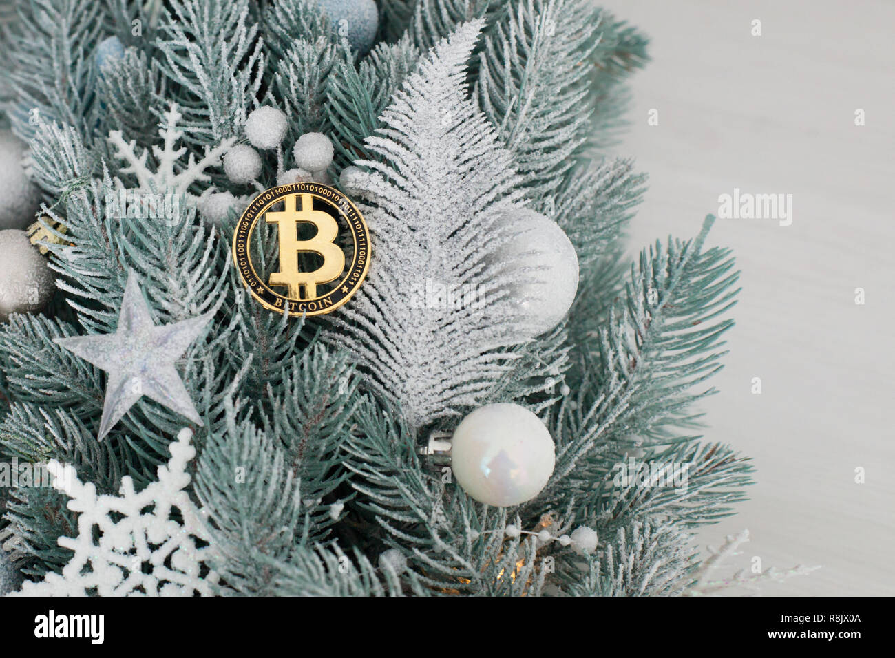 Bitcoin entre los juguetes de Navidad en las ramas del árbol de Navidad. Foto de stock