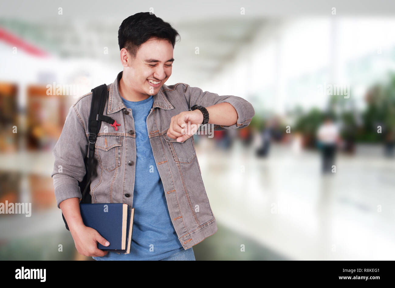 El concepto de tiempo, la imagen de foto retrato de un joven asiático lindo exitoso estudiante varón sonriendo y mirando su reloj de pulsera, de cerca de medio cuerpo vertical Foto de stock