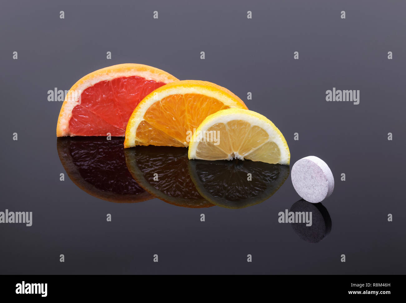 La toronja, naranja y limón en rodajas y una tableta de vitaminas .vitamina C natural versus vitaminas sintéticas. Foto de stock