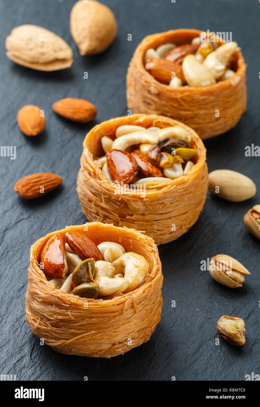 Tradicionales dulces de Oriente Medio 'nido de pájaro' en miel, jarabe con tuerca llenado - almendras, anacardos y pistachos. Baklava cerca. Un delicioso postre. S Foto de stock