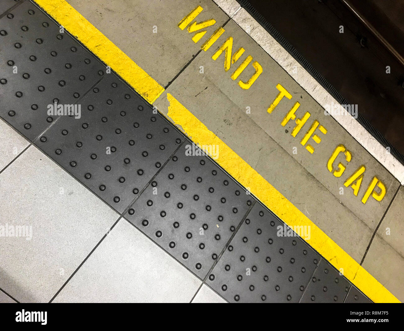 Foto inclinada de la mente la brecha firmar. Metro de Londres típica mente la brecha entre el tren y la plataforma. Foto de stock