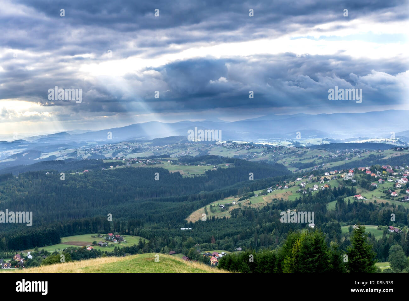 Rayos de sol a través de nubes sobre las montañas Beskydy Silesia. Vista sobre pueblo Koniakow Ochodzita desde el pico de la montaña. Polonia, Europa Foto de stock