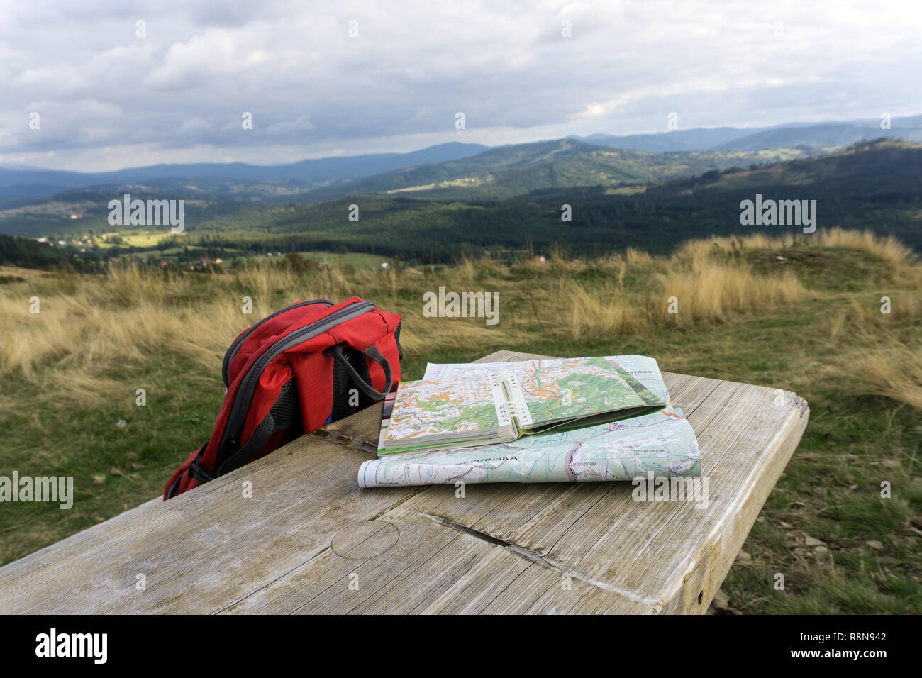 Banco de madera con mapas de caminatas y la mochila. Paisaje de montaña en el fondo, a nadie. Beskydy Silesia, Polonia. Foto de stock