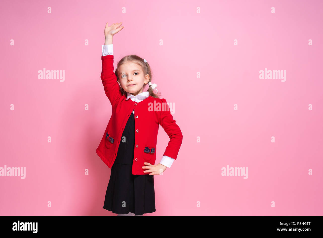 Niña diligente en brillante chaleco rojo y negro de prendas de vestir y  sonriente sosteniendo la mano mientras está de pie sobre fondo de color  rosa Fotografía de stock - Alamy