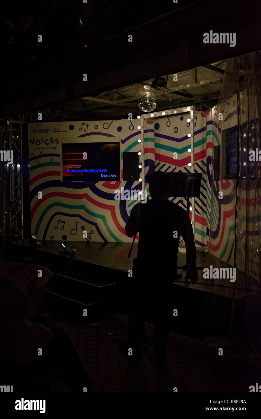 Cantante de karaoke en silueta, paseo de la Explanada, Singapur, Asoa
