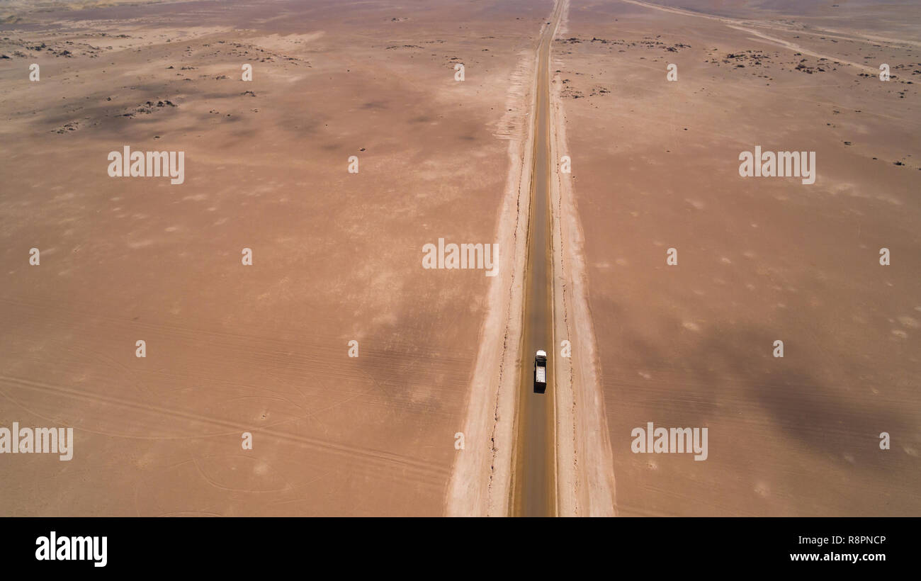 Vista aérea desde arriba al desierto de Atacama ruta solitaria, con un camión pasando Foto de stock