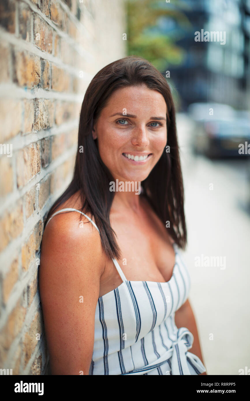 Confiados, retrato Mujer sonriente en la acera urbana Foto de stock