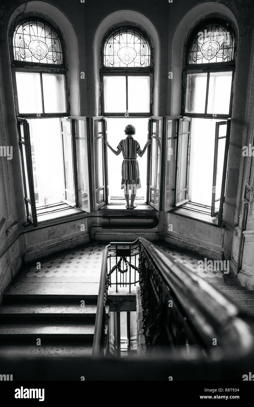 Suicidio chica quiere saltar fuera de la ventana de la mansión. Blanco y negro Foto de stock
