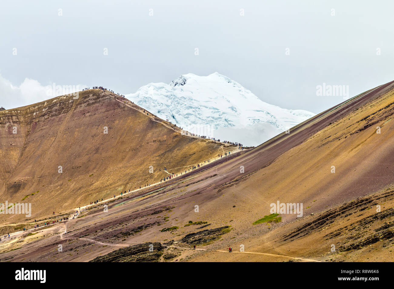 La gente de senderismo en la montaña de arco iris con el Ausangate glaciar en el fondo, Perú Foto de stock