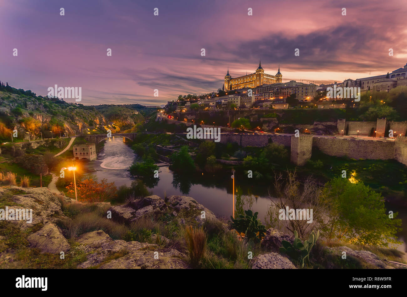 Toledo visto desde el otro lado del río Tajo al atardecer con el Alcázar de Toledo iluminada Foto de stock