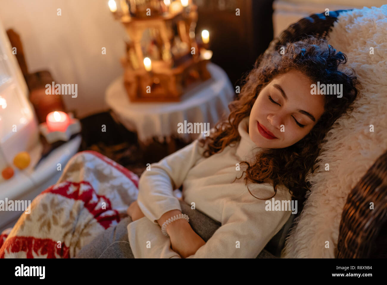 Hermosa mujer joven con el pelo rizado está tomando una siesta con las luces de Navidad en el fondo Foto de stock